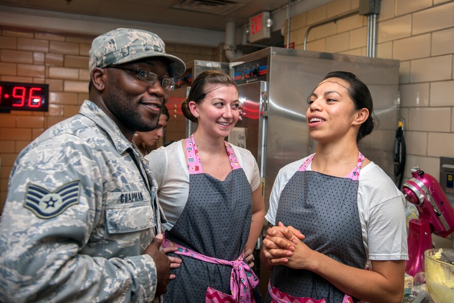 U.S. Air Force Staff Sgt. Michael Chapman interviews Senior Airman Brittany Serrano (middle) and Capt. Melissa Garcia, both of team Shake-N-Bake, during Cupcake Wars 3 at Moody Air Force Base, Ga., July 23, 2013.  Chapman acted as the event’s host, interviewing teams and commenting on their progress as it was live streamed to the audience in another room. (U.S. Air Force photo by Senior Airman Jarrod Grammel/Released)
