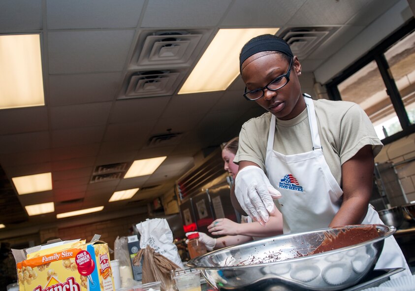 U.S. Air Force Airman 1st Class Neporsha Mobley, Trading Places team member, throws ingredients into a mixing bowl during Cupcake Wars 3 at Moody Air Force Base, Ga., July 23, 2013. The teams had to bake three different cupcakes with at least one of the three containing tropical fruit. (U.S. Air Force photo by Senior Airman Jarrod Grammel/Released)
