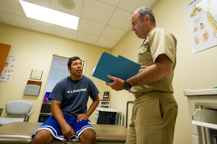 Navy Lt. Gregory Norris, Naval Health Clinic Charleston physical therapist, reviews medical information with Petty Officer 1st Class Dan Coen, a U.S. Coast Guard Sector Charleston electronics technician July 29, 2013, at Joint Base Charleston - Weapons Station, Goose Creek, S.C. NHCC provides quality healthcare services for approximately 12,000 beneficiaries throughout the LowCountry, including a sick call clinic for Sailors assigned to the Weapons Station. (U.S. Air Force photo/ Senior Airman George Goslin)