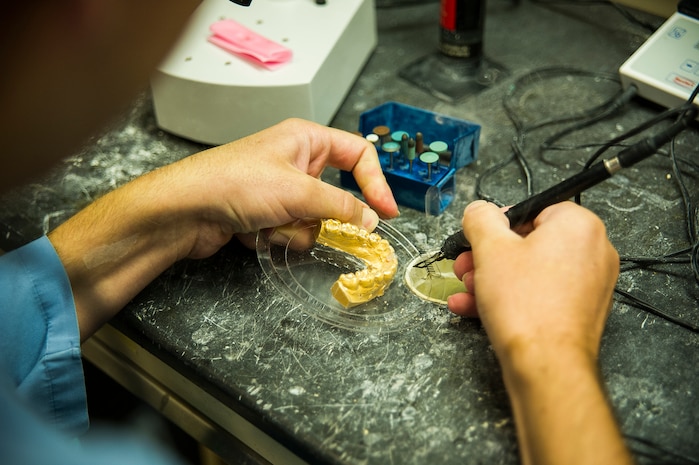 Navy Lt. Clay Miller, Naval Health Clinic Charleston dental officer, makes a temporary partial denture using a Therma-Knife July 29, 2013, at Joint Base Charleston - Weapons Station, Goose Creek, S.C. The Therma-Knife produces clean cuts through plastic fiber of all types and diameters as an alternative to polishing or cutting. (U.S. Air Force photo/ Senior Airman George Goslin)