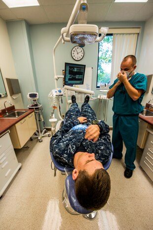 Lt. Cmdr. Joshua Henson, Naval Health Clinic Charleston senior dental executive, adjusts his mask as he prepares to perform a patient exam July 29, 2013, at Joint Base Charleston - Weapons Station, Goose Creek, S.C. NHCC provides quality healthcare services for approximately 12,000 beneficiaries throughout the LowCountry, including a sick call clinic for Sailors assigned to the Weapons Station. (U.S. Air Force photo/ Senior Airman George Goslin)