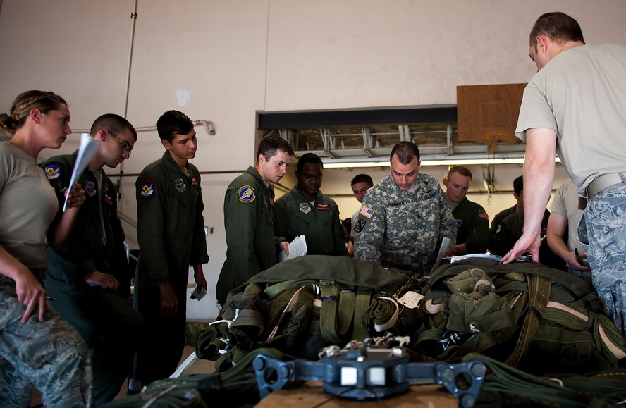 U.S. Army Staff Sgt. Simon Fonseca, Aerial Delivery Field Services Department, reviews discrepancies on airdrop bundle with members of the 317th Airlift Group July 25, 2013 during a recertification class at Dyess Air Force Base, Texas. With limited funds available to keep the 317th Airlift Group flying, leadership within the organization found a way to ensure 45 Airmen behind the scenes stay certified to keep the C-130s in the air -all while saving $85,000, by sending instructors here to teach required courses. (U.S. Air Force photo by Airman 1st Class Damon Kasberg/Released)