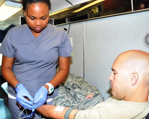 Technical Sgt. Ryan Belcher, 507th Operations Support Flight, watches as Oklahoma Blood Institute phlebotomist Bryana Martin checks his arm and the tubing as he donates blood. The OBI bloodmobile was at the 507th Air Refueling Wing during the July UTA to collect donations. More than 30 reservists gave blood during the event. (U.S. Air Force Photo/Lt. Col. Kim Howerton)