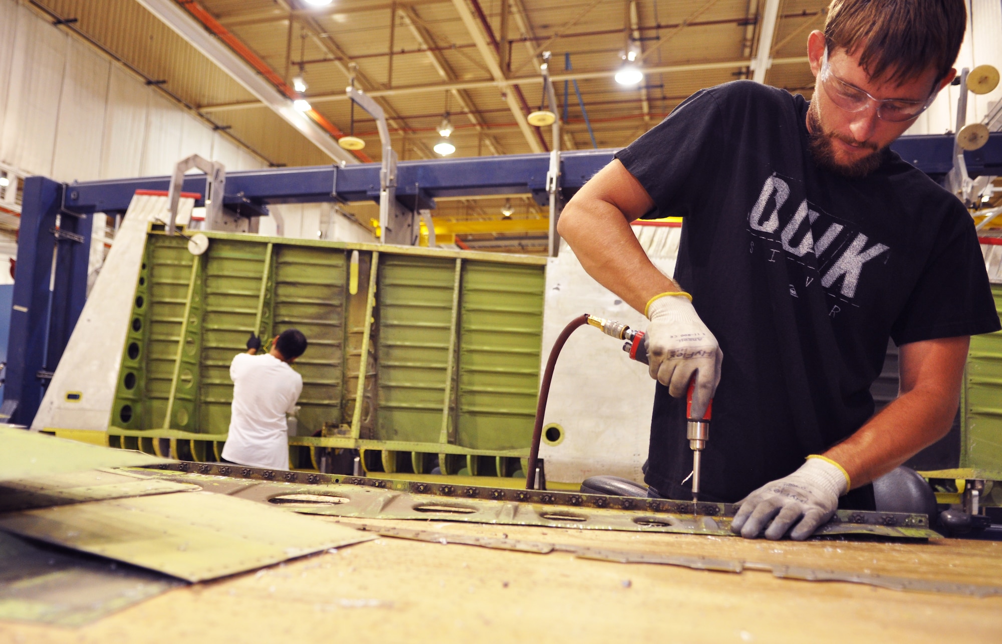 William Wiens, front, repairs a piece of a rudder’s internal structural web while Thomas Pham cleans the rudder and checks for structural corrosion. The 551st Commodities Maintenance Squadron shop in Bldg. 9001 repairs approximately 80 rudders from KC-135 Stratotankers and E-3 Sentrys each year. (Air Force photo by Micah Garbarino)