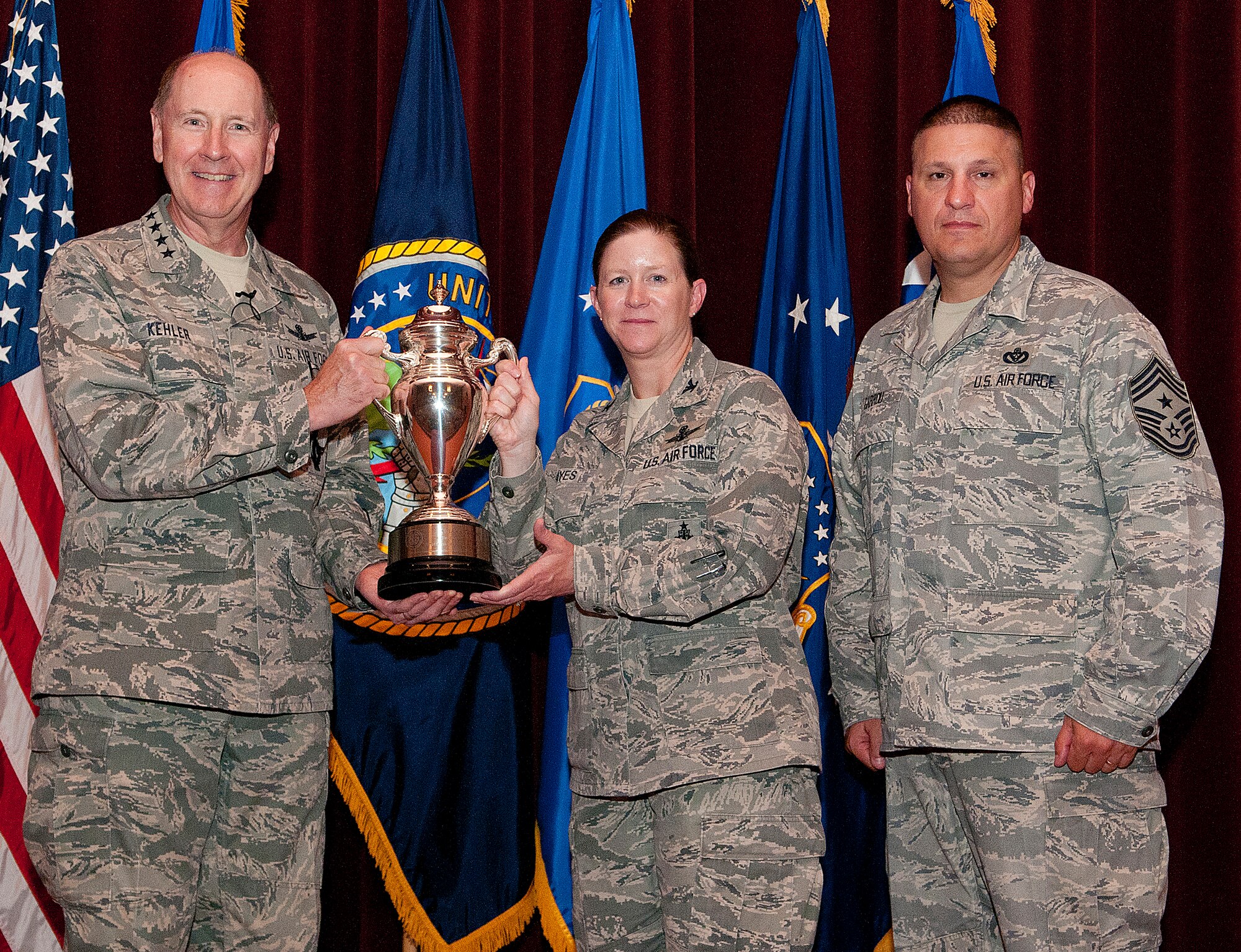 Gen. C. Robert Kehler, U.S. Strategic Command commander, presents the Omaha Trophy to Col. Tracey Hayes, 90th Missile Wing commander, and Chief Master Sgt. Mike Garrou, 90th MW command chief, during an all-call at the F.E. Warren Air Force Base, Wyo., theater July 30, 2013. The Omaha Trophy is award to the best missile wing in USSTRATCOM. (U.S. Air Force photo by R.J. Oriez) 