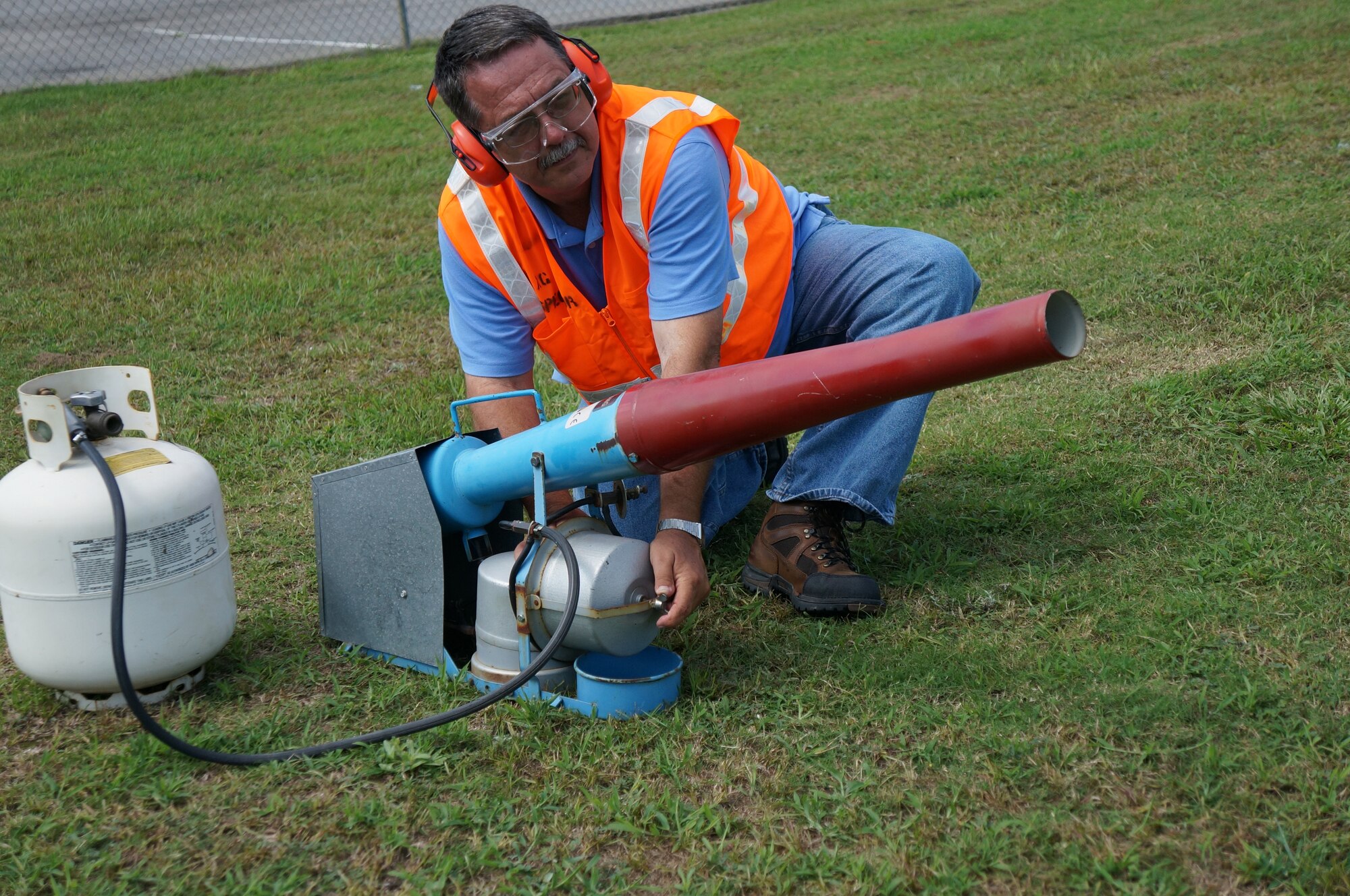 Ken Corley, pest controller, demonstrates one of two bird-scare canons, which are noisemakers that frighten birds away from the path of aircraft. (U.S. Air Force photo by Jenny Gordon)
