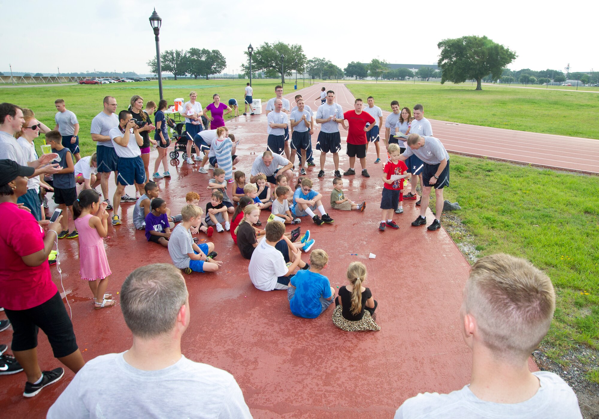 Maj James Coughlin, 85th Engineering Installation Squadron commander, presents coupons for free ice cream to children participating in the squadron's family physical training day July 26, 2013, at the Triangle Track, Keesler Air Force Base, Miss. The event included stretching and exercise for squadron members and their families and concluded with a water balloon fight. (U.S. Air Force photo by Adam Bond)