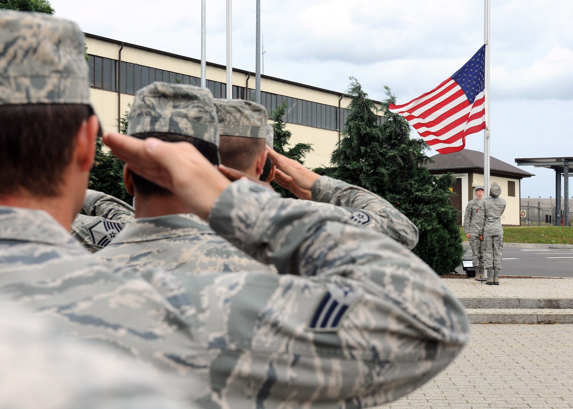 SPANGDAHLEM AIR BASE, Germany – Base members salute as honor guard members lower the U.S. flag at a new retreat ceremony July 29, 2013. U.S. Air Force Chief Master Sgt. Matthew Grengs, 52nd Fighter Wing command chief master sergeant, initiated the base-wide retreat ceremony as a way for Spangdahlem Airmen to demonstrate military customs and courtesies. (U.S. Air Force photo by Staff Sgt. Daryl Knee/Released)