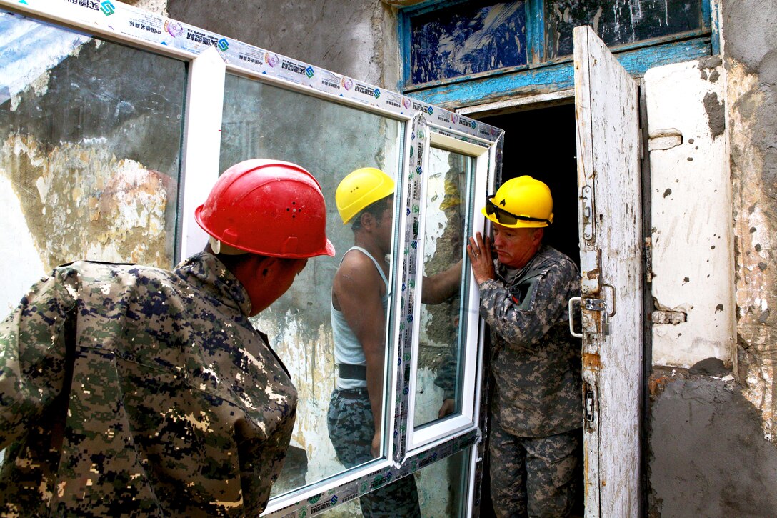U.S. Army Sgt. Phil E. Chavez, right, assists Mongolian armed forces engineers during renovation work on Erdmiin Oyun High School as part of Exercise Khaan Quest 2013 in Ulaanbaatar, Mongolia, July 25, 2013. Chavez, a combat engineer, is assigned to the Washington Army National Guard's 176th Engineer Company, Vertical, 96th Troop Command.