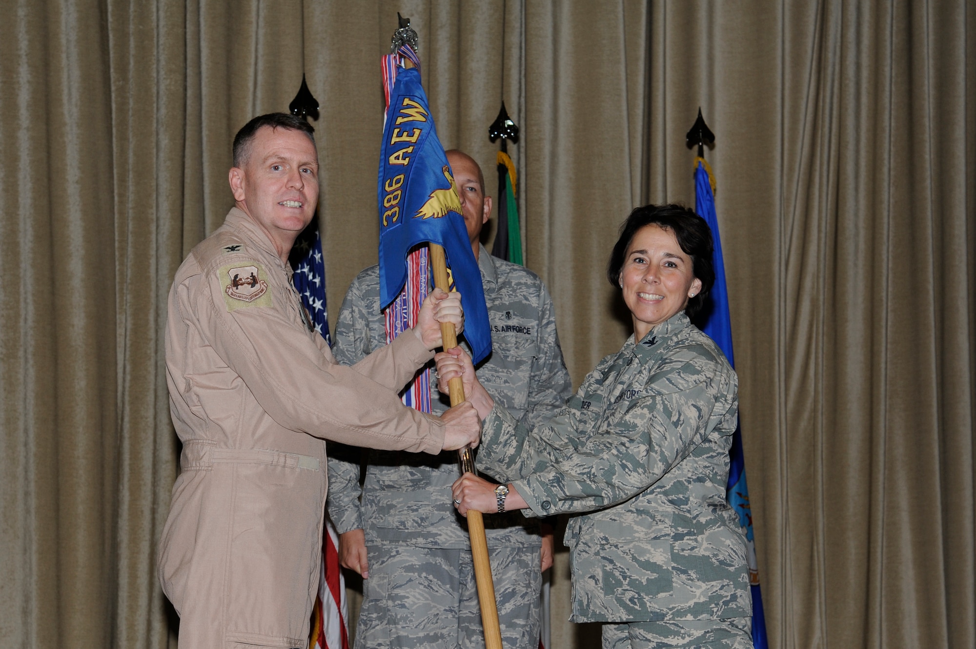 Col. David Farrow, 386th Air Expeditionary Wing commander, left, passes the 386th Expeditionary Medical Group guidon to Col. Jeannine Ryder during a change of command ceremony June 1, 2013 at an undisclosed location in Southwest Asia.  Col. Ryder assumed command of the 386th EMDG from Col. Virginia Garner.  (U.S. Air Force photo by Staff Sgt. Austin Knox)
