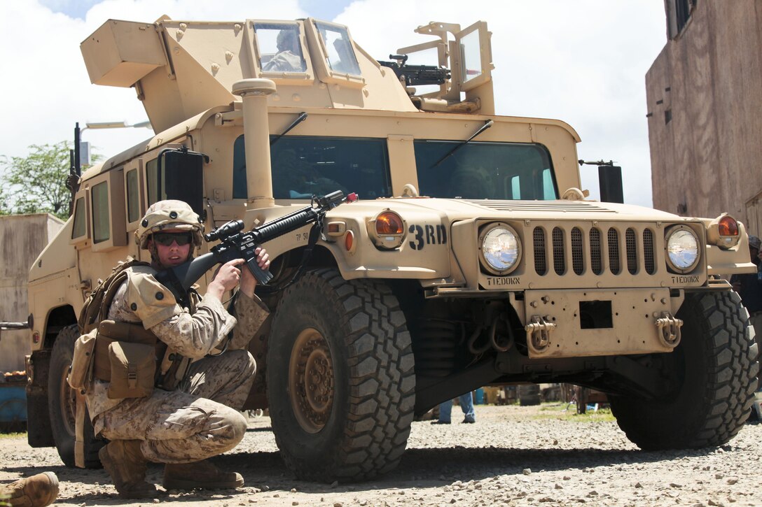 U.S. Marine Corps Private First Class Ethan A. Carson, a Motor Transport Operator with Combat Logistics Battalion Three (CLB-3), provides cover and support from behind the front of a High Mobility Multi Wheeled Vehicle(HMMWV) during a humanitarian assistance disaster relief operation at Marine Corps Training Area Belllows on May 15th, 2013. The operation was in conjunction with chemical, biological, radiological, and nuclear training as part of CLB-3's battalion final exercise. 