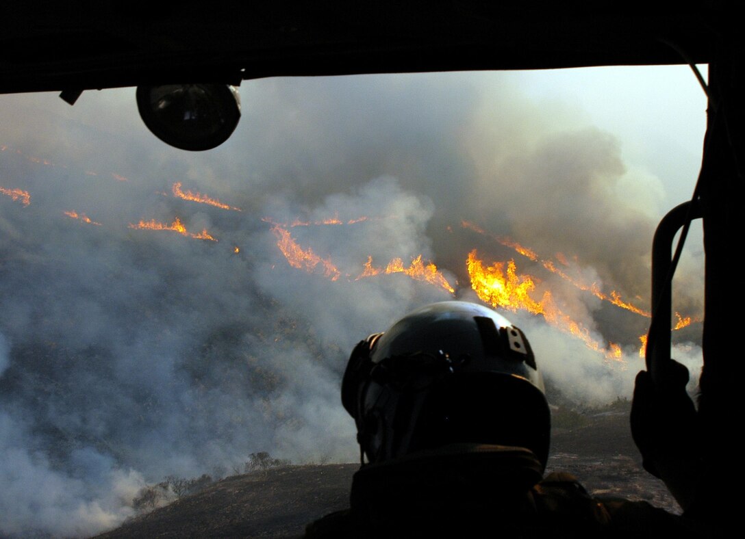 071023-N-2183K-085
Calif. (Oct. 23, 2007) – Aviation Warfare Systems Specialist 3rd Class Zach Sykora, attached to Helicopter Sea Combat Squadron Eight Five (HSC) 85, searches for a burning target to dump 420 gallons of water on.  HSC-85 has teamed up with the San Diego California Department of Forestry and Fire Protection to put out the wild fires blazing across Southern California.        