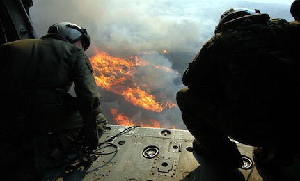 Crew members aboard a MH-60s Seahawk helicopter activate a release button, dumping 420 gallons of water below them on a burning target.  HSC-85 has teamed up with the San Diego California Department of Forestry and Fire Protection to put out the wild fires blazing across Southern California.          
