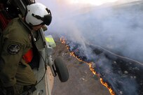 Aviation Warfare Systems Specialist 3rd Class Zach Sykora, attached to Helicopter Sea Combat Squadron Eight Five (HSC) 85, searches for a burning target to dump 420 gallons of water on.  HSC-85 has teamed up with the San Diego California Department of Forestry and Fire Protection to put out the wild fires blazing across Southern California.                                  