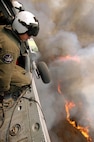 Aviation Warfare Systems Specialist 3rd Class Zach Sykora, attached to Helicopter Sea Combat Squadron Eight Five (HSC) 85, searches for a burning target to dump 420 gallons of water on.  HSC-85 has teamed up with the San Diego California Department of Forestry and Fire Protection to put out the wild fires blazing across Southern California.                                  