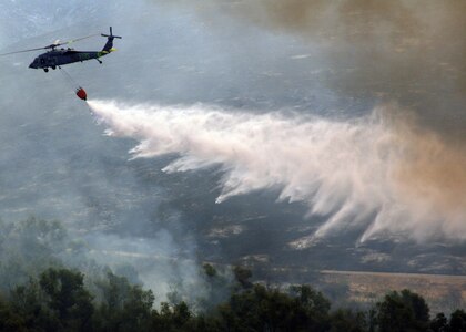 An MH-60S "Knighthawk" from Helicopter Sea Combat Squadron (HSC) 85, the "High Rollers" dumps a full 420-gallon capacity extinguishing trough today onto of one of the many areas across the San Diego county suffering from an ongoing wildfire.

The fiery disaster has already forced more than 250,000 people from their homes across the San Diego county.

