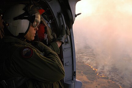 Chief Aviation Electronics Mate (AW/NAC) Rexford Sackett from the "High Rollers" of Helicopter Sea Combat (HSC) Squadron 85 looks from a MH-60S Knighthawk upon miles of burnt terrain along the San Diego County as he and other Sailors from HSC-85 prepare to help fend off the blaze.

The High Rollers provided two MH-60S each specially equiped with a 420 gallon-capacity extinguishing trough used to dump massive amounts of water on San Diego's ongoing fire disaster. 

The dangerous blaze has already forced more than 250,000 people from their homes.

