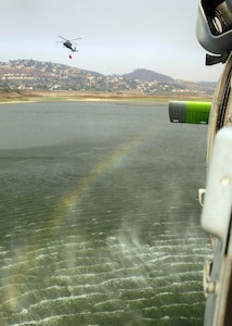 An MH-60S "Knighthawk" from Helicopter Sea Combat Squadron (HSC) 85, the "High Rollers" lifts a full 420-gallon capacity extinguishing trough today from a local resevoir as another MH-60S flies up to fill their trough.

The trough allows massive amounts of water to be dumped on San Diego's ongoing fiery disaster that has already forced more than 250,000 people from their homes across the San Diego county.

