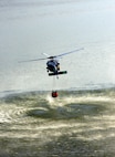 A MH-60s Seahawk helicopter from Helicopter Sea Combat Squadron Eight Five (HSC) 85, pulls 420 gallons of water from a reservoir using a “Bambi Bucket.”  HSC-85 has teamed up with the San Diego California Department of Forestry and Fire Protection to put out the wild fires blazing across Southern California.  