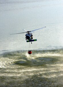 A MH-60s Seahawk helicopter from Helicopter Sea Combat Squadron Eight Five (HSC) 85, pulls 420 gallons of water from a reservoir using a “Bambi Bucket.”  HSC-85 has teamed up with the San Diego California Department of Forestry and Fire Protection to put out the wild fires blazing across Southern California.  