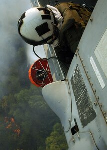 Aviation Warfare Systems Operator 3rd Class (NAC) William Quadrino from the "High Rollers" of Helicopter Sea Combat Squadron (HSC) 85 drops water from a Navy MH-60S "Seahawk" Tuesday that was specially equipped with a 420 gallon-capacity Bambi bucket.

HSC-85 flew two MH-60S each specially equipped with a 420 gallon-capacity Bambi bucket.

