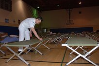 Culinary Specialist 2nd Class (SW) Yan Ng, of the Naval Medical Center San Diego Director for Administration Bachelors Enlisted Quarters Department, prepares cots for potential evacuees during the San Diego wildfires, which have burned more than 240,000 acres in San Diego County. 

U.S. Navy photo by Mass Communication Specialist 2nd Class (AW) Greg Mitchell. 