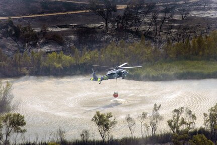 An MH-60S Seahawk helicopter retrieves water from a lake near the wildfires in San Diego. Helicopter Sea Combat Squadron (HSC) 85 has teamed up with the San Diego California Department of Forestry and Fire Protection to help put out the wildfires blazing across Southern California. 

U.S. Navy photo by Mass Communication Specialist Seaman Jon Husman 

