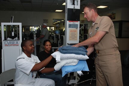 Hospital Corpsman Senior Chief (FMF/NAC) Trevor Dallas-Orr, Naval Medical Center San Diego Special Projects Officer for the Command Master Chief, hands blankets and pillows to Personnel Specialist 1st Class (SW/AW) William Clincy and his wife Iris during their stay at the temporary evacuation site. NMCSD provided community support and assistance during the San Diego wildfire which has claimed more than 240,000 acres of land in San Diego County. 