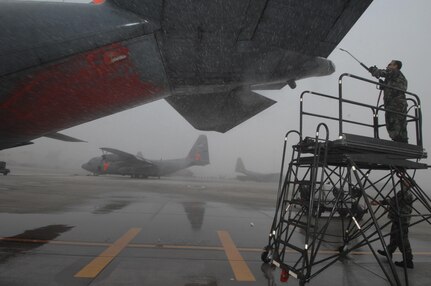 Senior Airman Leo Alvarado and Tech. Sgt Kriss Todd of the 153rd Aircraft Maintenance Engine Shop in Cheyenne, Wyoming. pressure wash fire retardant off of a C-130 in the early morning awaiting during a flight delay due to low visibility/weather conditions at Channel Islands Air National Guard Station, Calif., on Oct. 26, 2007 in support of the California firefighting efforts. The U.S. Air Force Reserve and Air National Guard are participating in the Southern California firefighting effort. 