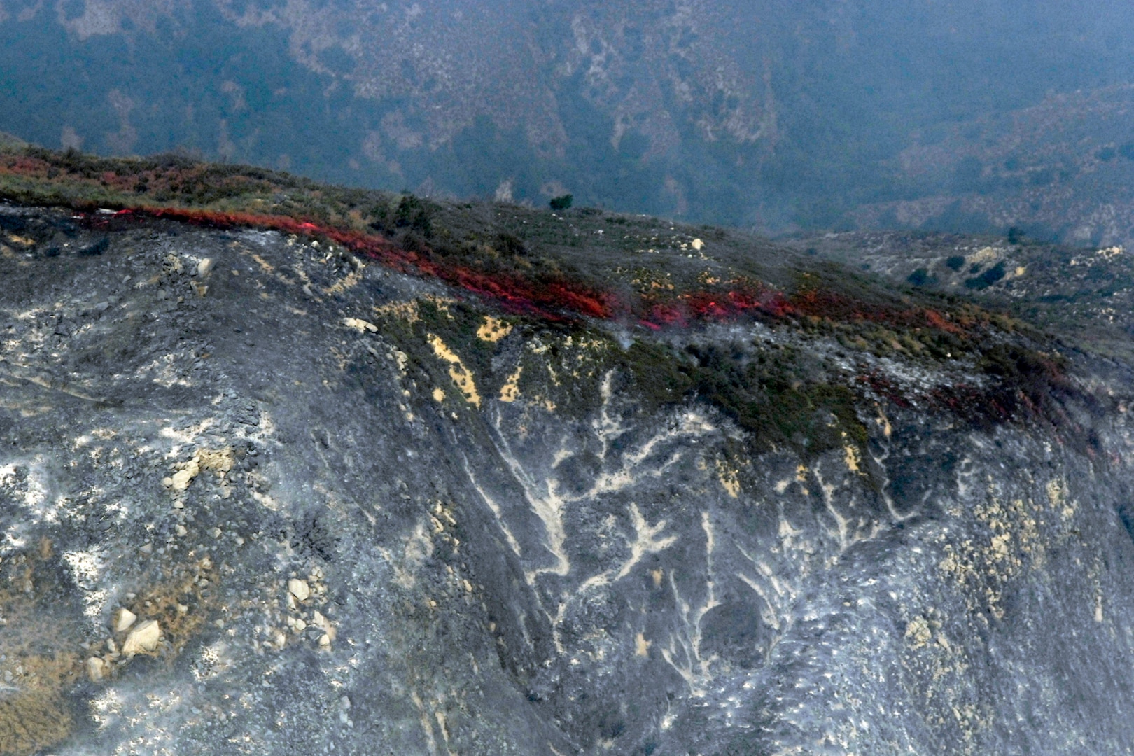 Fire retardant lines are placed in front of the advancing Poomacha fire burning in the Mount Palomar area. C-130s launched from Channel Islands Air National Guard Station, Calif., Oct., 26, 2007 are participating in the Southern California firefighting effort. 