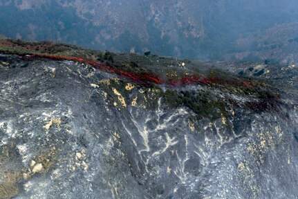 Fire retardant lines are placed in front of the advancing Poomacha fire burning in the Mount Palomar area. C-130s launched from Channel Islands Air National Guard Station, Calif., Oct., 26, 2007 are participating in the Southern California firefighting effort. 