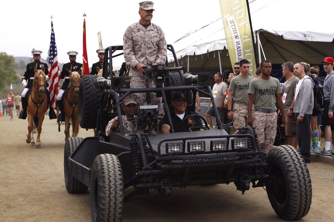 Brig. Gen. Vincent A. Coglianese, top, Sgt. Maj. Derek Christovale Sr., bottom left, enter the staging area in a Chenowth Advanced Light Strike Vehicle before giving opening remarks at the 20th annual World Famous Mud Run here June 1. Several obstacles were incorporated into the 10K, which started at Lake O’Neil, and took the runners through training areas 26 and 27 of the base.