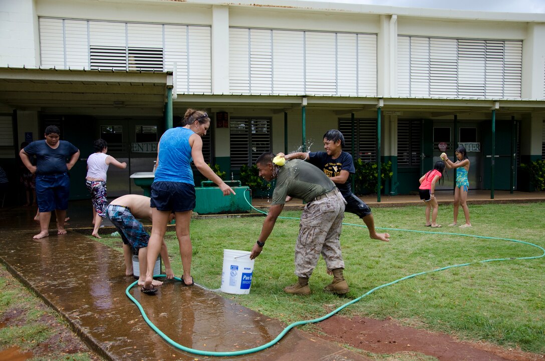 Fifth grader Kaiwi Giltner squeezes a water-filled sponge on Lance Cpl. Juan David Taborda, an administrative clerk with the Adjutant’s Office, during Kailua Elementary School’s Ho Ike picnic and water play day on campus, May 17, 2013. (U.S. Marine Corps photo by Kristen Wong)