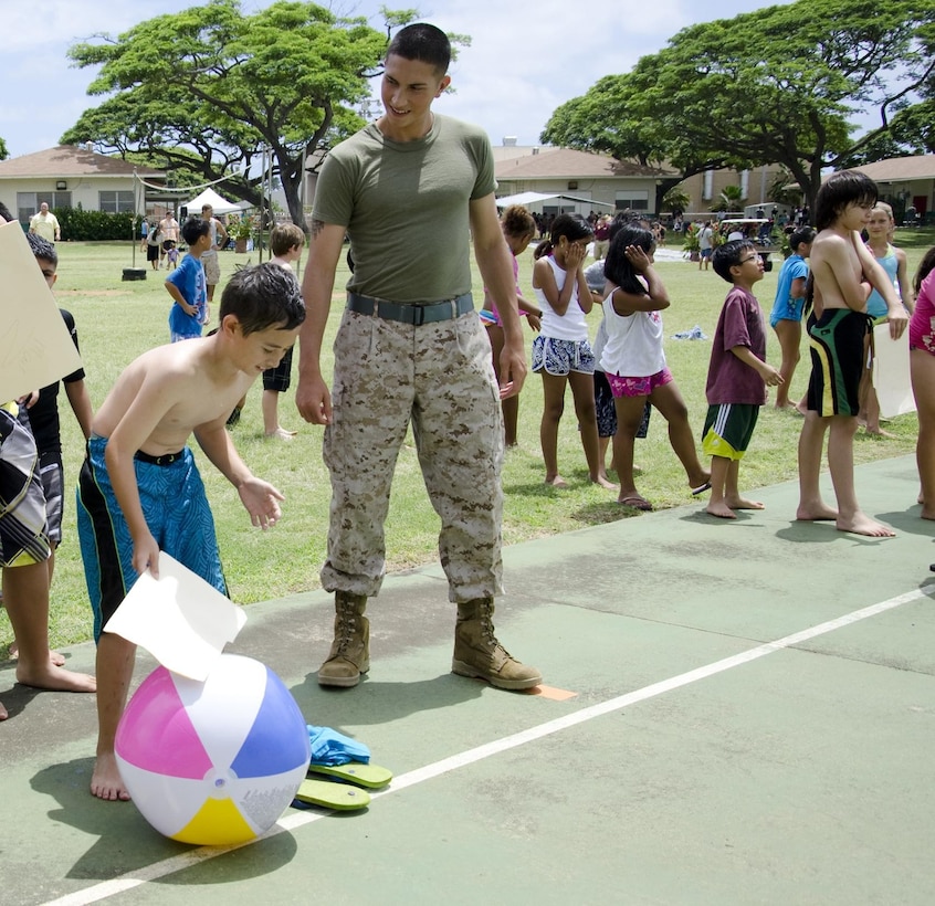 Pfc. Steven Mafla, an administration clerk with Installation Personnel Administration Center chats with students in line as fourth grader Aisea Ahokovi gets ready to play a beach ball game during Kailua Elementary School’s Ho Ike picnic and water play day on campus, May 17, 2013. Mafla, of Pomona, Calif., was one of the volunteers from Manpower, Personnel and Administration who manned a game station for the event. (U.S. Marine Corps photo by Kristen Wong)
