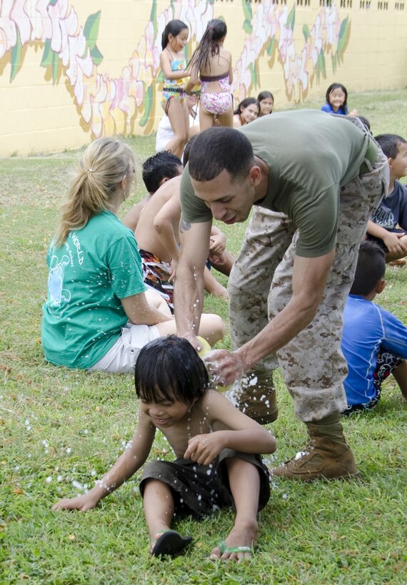 Sgt. Demetrio DiazCabrera, Manpower, Personnel and Administration chief, tags first grader Brayden Lauronal with a wet sponge while playing “Duck, duck, goose” during Kailua Elementary School’s Ho Ike picnic and water play day on campus, May 17, 2013. (U.S. Marine Corps photo by Kristen Wong)