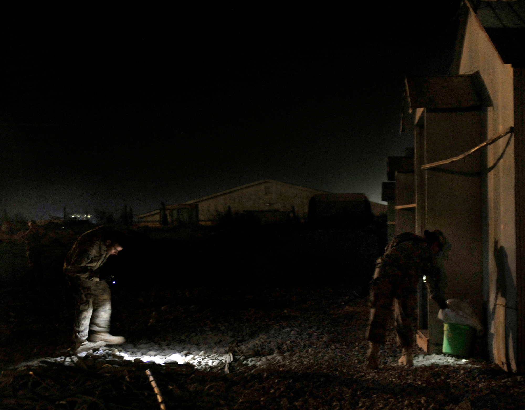 Task Force Colonist volunteers search the exterior of a compound for hidden, unauthorized items on Bagram Airfield, Afghanistan May 30.  Task Force Colonist is a force protection tool used to conduct random camp sweeps of third country national employee living areas for illegal items such as drugs, weapons, unauthorized uniform items, and/or electronic devices. (U.S. Air Force photo/ Staff Sgt. Stephenie Wade)