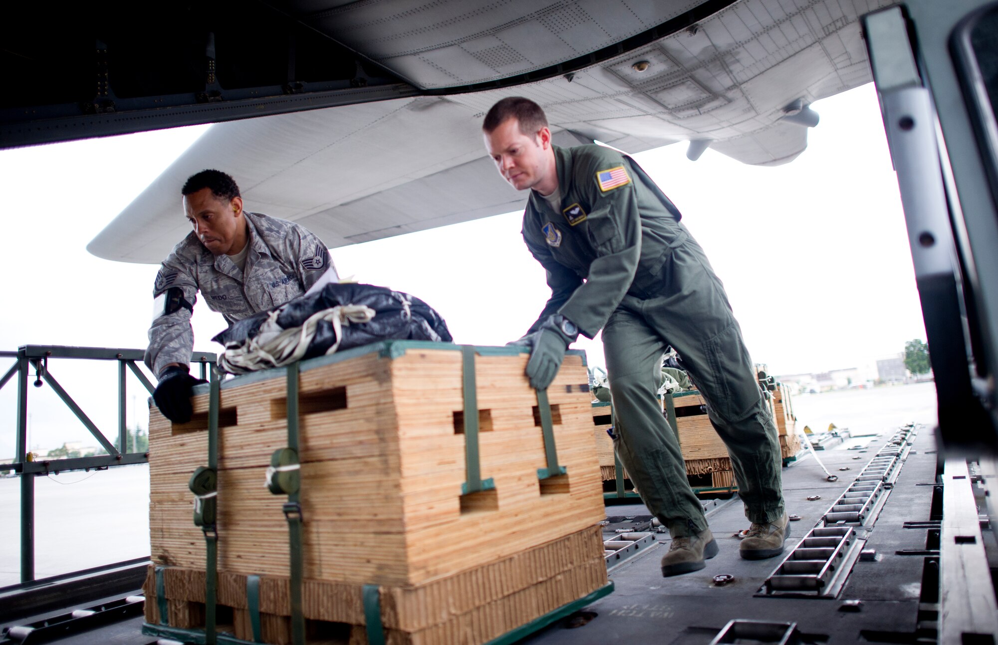 YOKOTA AIR BASE, Japan -- (left to right) Staff Sgt Watani Redo air transportation specialist and SSgt Chris Nichols, loadmaster,  with the 36th Airlift Squadron, transfer a low cost low altitude bundle from the Halverson 25K loader to a C-130 aircraft May 29, 2013 at Yokota Air Base, Japan. The LCLA bundles are being loaded and dropped during exercise Airborne Tomahawk with joint services. Exercise will participants evaluate rigging and movement procedures and execute airdrop resupply. (U.S. Air Force photo by Staff Sgt. Stacy Moless)  