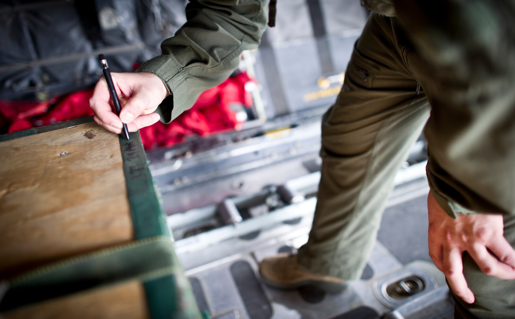 YOKOTA AIR BASE, Japan -- Senior Airman Noel Jones, loadmaster with the 36th Airlift Squadron, marks a low cost low altitude bundle before takeoff, May 29, 2013 at Yokota Air Base, Japan. These LCLA's are used for training, usually consisting of jerry cans, ammo cases and wood rigged together. (U.S. Air Force photo by Staff Sgt. Stacy Moless)