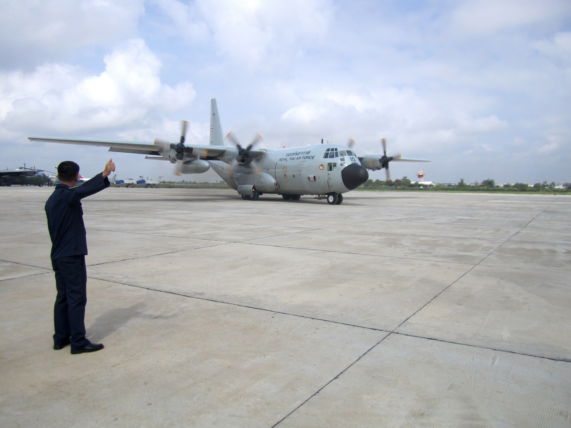 POCHENTONG AIR BASE, Cambodia -- A member of the Royal Thai Air Force guides a RTAF C-130 on the taxiway here prior to its first flight in Pacific Airlift Rally 2013 June 3, 2013. PAR13 is co-hosted by the U.S. and the Royal Cambodian Air Forces. U.S. servicemembers are participating in PAR13, which advances military airlift interoperability and cooperation between the nations of the Indo-Pacific region. (U.S. Air Force photo/Capt. Chris Hoyler)