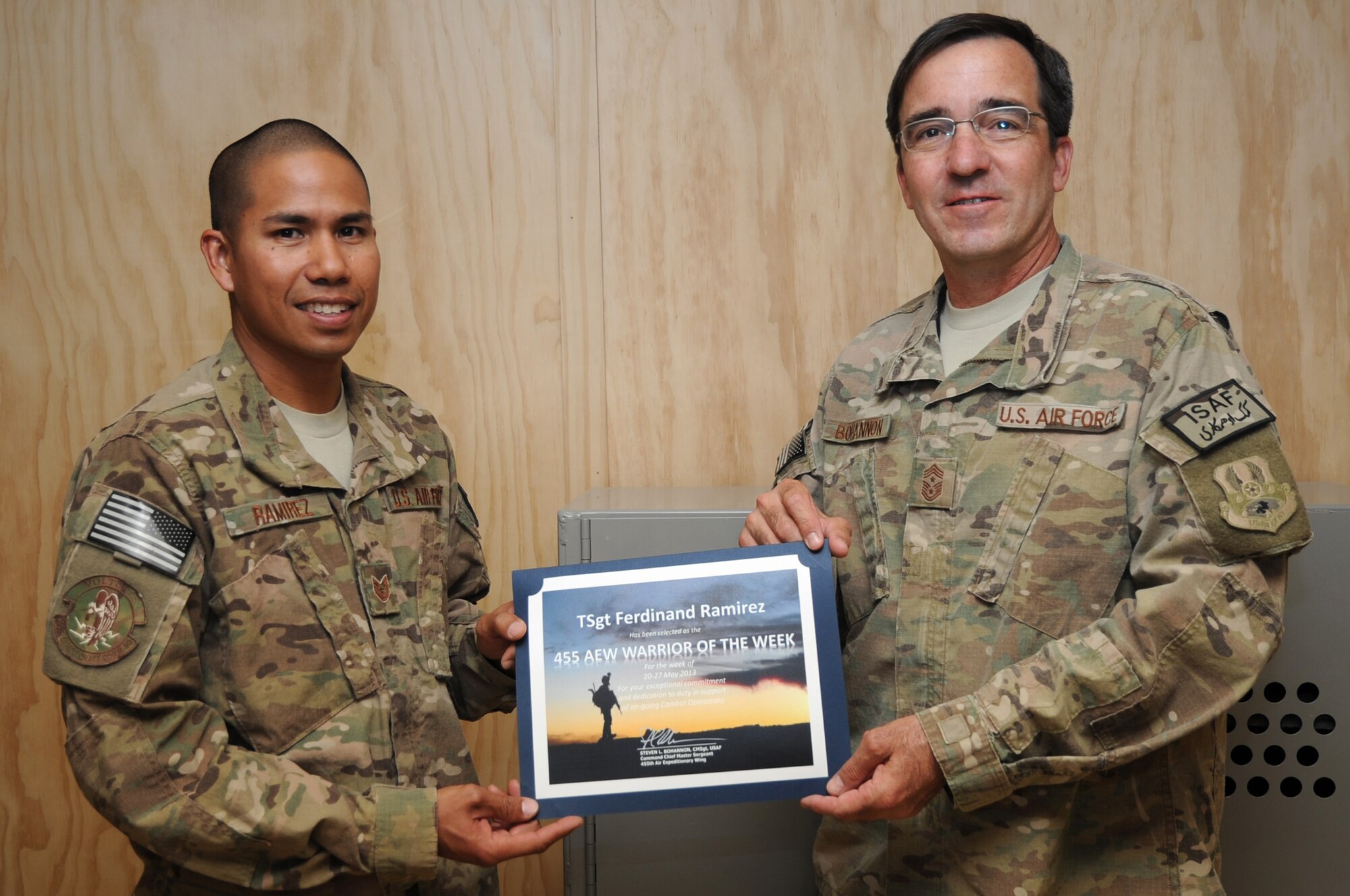 Chief Master Sgt. Steve Bohannon, Command Chief Master Sergeant of the 455th Air Expeditionary Wing, presents the "Warrior of the Week" award to Tech. Sgt. Ferdinand Ramirez, 455th Expeditionary Communications Squadron NCO in charge of cable maintenance, on Bagram Airfield, Afghanistan, May 29, 2013. Ramirez is responsible for overseeing upgrades to command and control of networks linking Bagram with 11 forward operating bases. (U.S. Air Force photo/Staff Sgt. David Dobrydney)