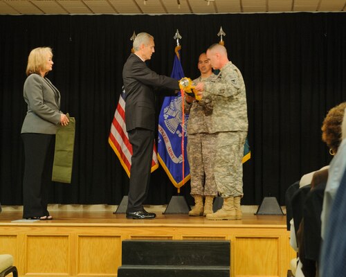 Sandra Sexton, Anniston Chemical Activity chief of staff, holds a canvas sleeve as Jesse Brown III, ANCA civilian executive, and Col. Darryl Briggs, U.S. Army Chemical Materials Agency Director of Stockpile Operations, roll up the ANCA flag that is being held by Anniston Army Depot Sgt. Maj. Jeffrey Marcon at a program commemorating the history of the Anniston Chemical Activity during a closure ceremony.