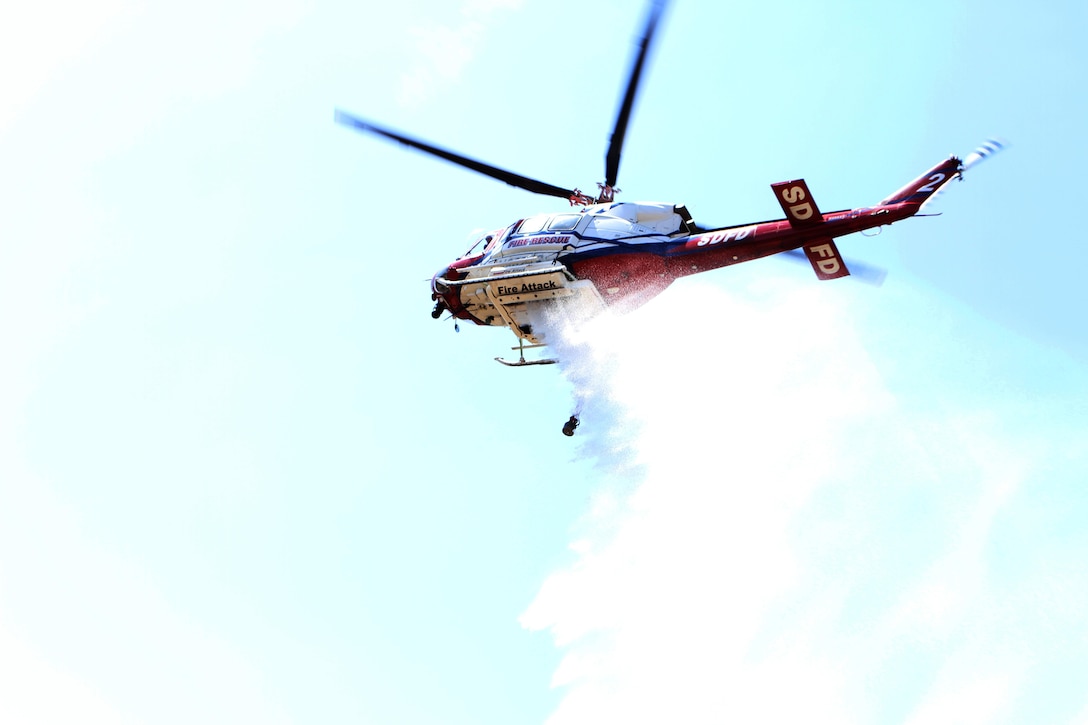 Copter 2 of San Diego Fire-Rescue Department’s Air Operations Division dumps a load of water during in-service fire training at Lake Hodges in Escondido, Calif. May 30. Engine 62 of the Miramar Fire Department was one of three engines battling the simulated wildland fire from the left flank, alongside two other engines working on the right flank.