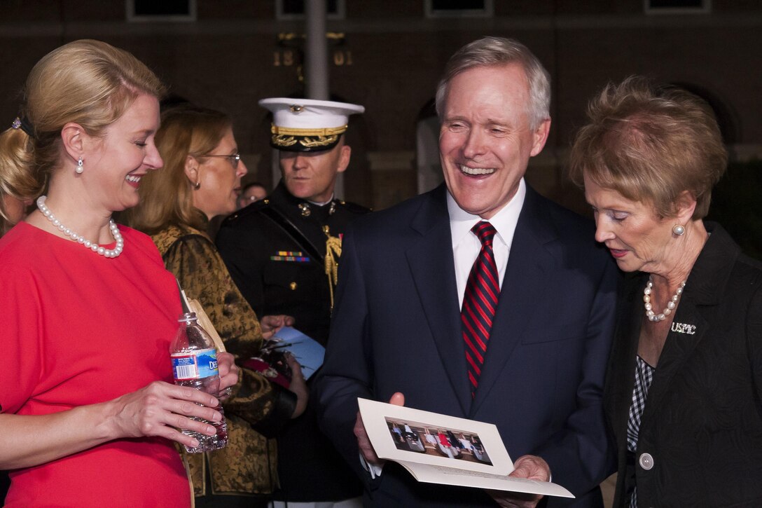 The Honorable Ray Mabus, Secretary of the Navy, center, his wife Lynne Mabus, left, and Bonnie Amos, first lady of the Marine Corps, right, smile at a gift presented to him at the conclusion of a Friday Evening Parade at Marine Barracks Washington, D.C., May 31. Mabus was the guest of honor of the parade. 
