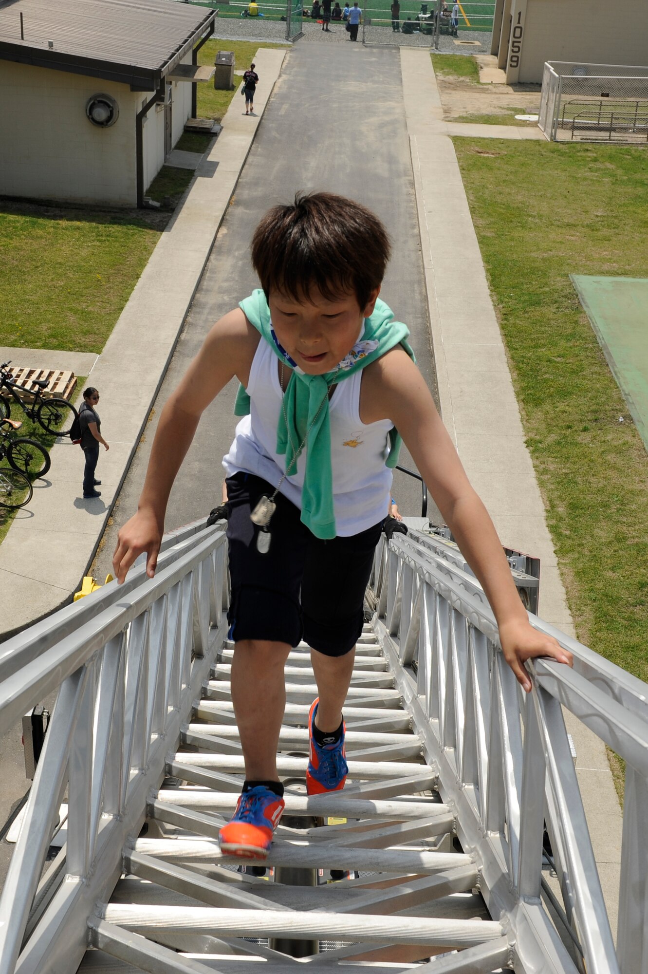 A child from the Ilmagwon Orphanage walks up a fire ladder during a sports day event for the youth at Kunsan Air Base, Republic of Korea, May 11, 2013. The children participated in soccer, basketball, bean bags toss and baseball. They watched demonstrations from the 8th Civil Engineer Squadron firefighters and 8th Security Forces Squadron military working dog section. (U.S. Air Force photo by Senior Airman Marcus Morris/Released)