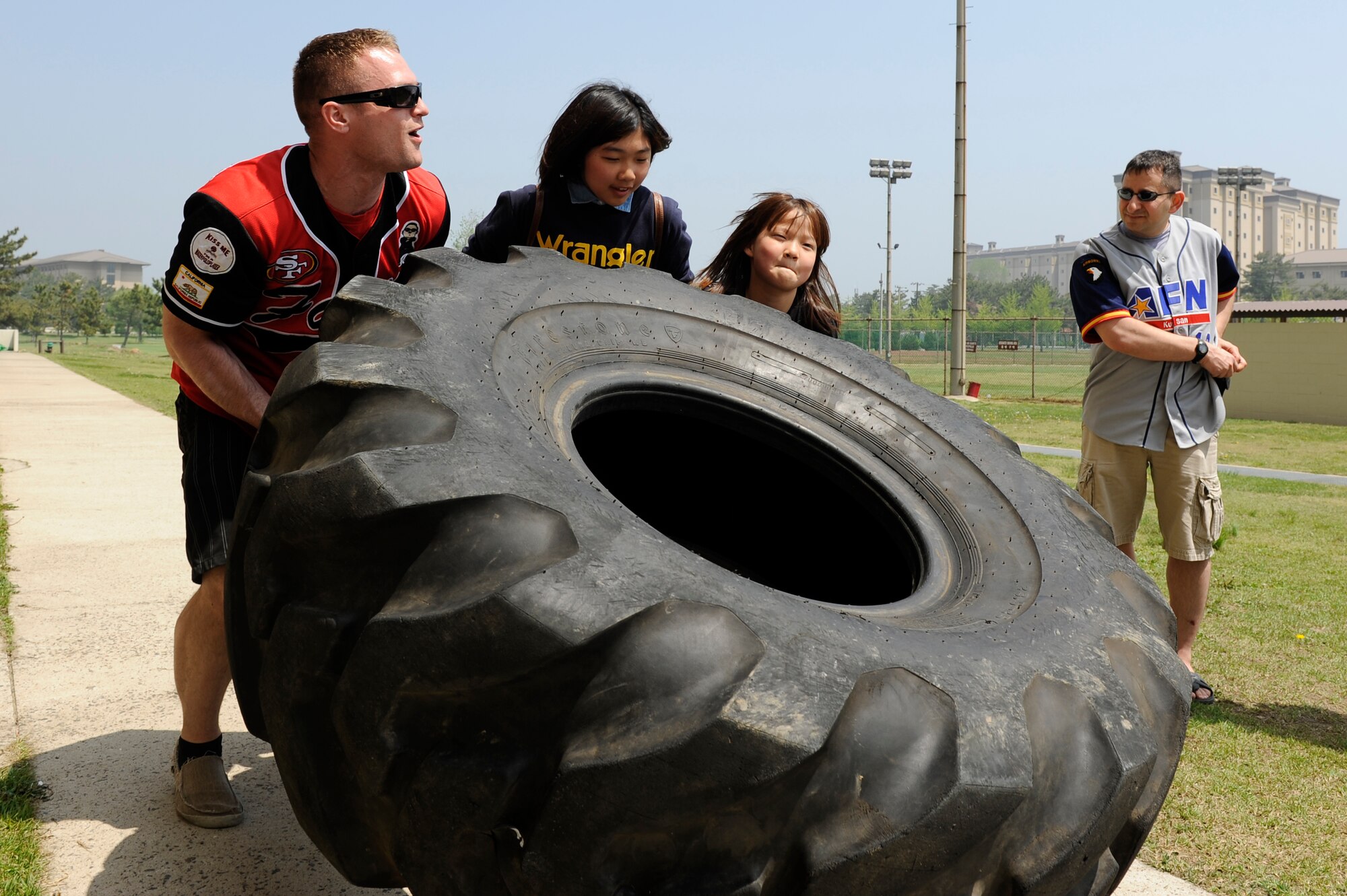 Senior Airman Spencer Hardesty, 8th Logistics Readiness Squadron, fire truck vehicle maintainer, helps youth from Ilmagwon Orphanage flip a tire during a sports day event at Kunsan Air Base, Republic of Korea, May 11, 2013. Airmen from Kunsan have been involved with the children of Ilmagwon Orphanage since 1968. (U.S. Air Force photo by Senior Airman Marcus Morris/Released)
