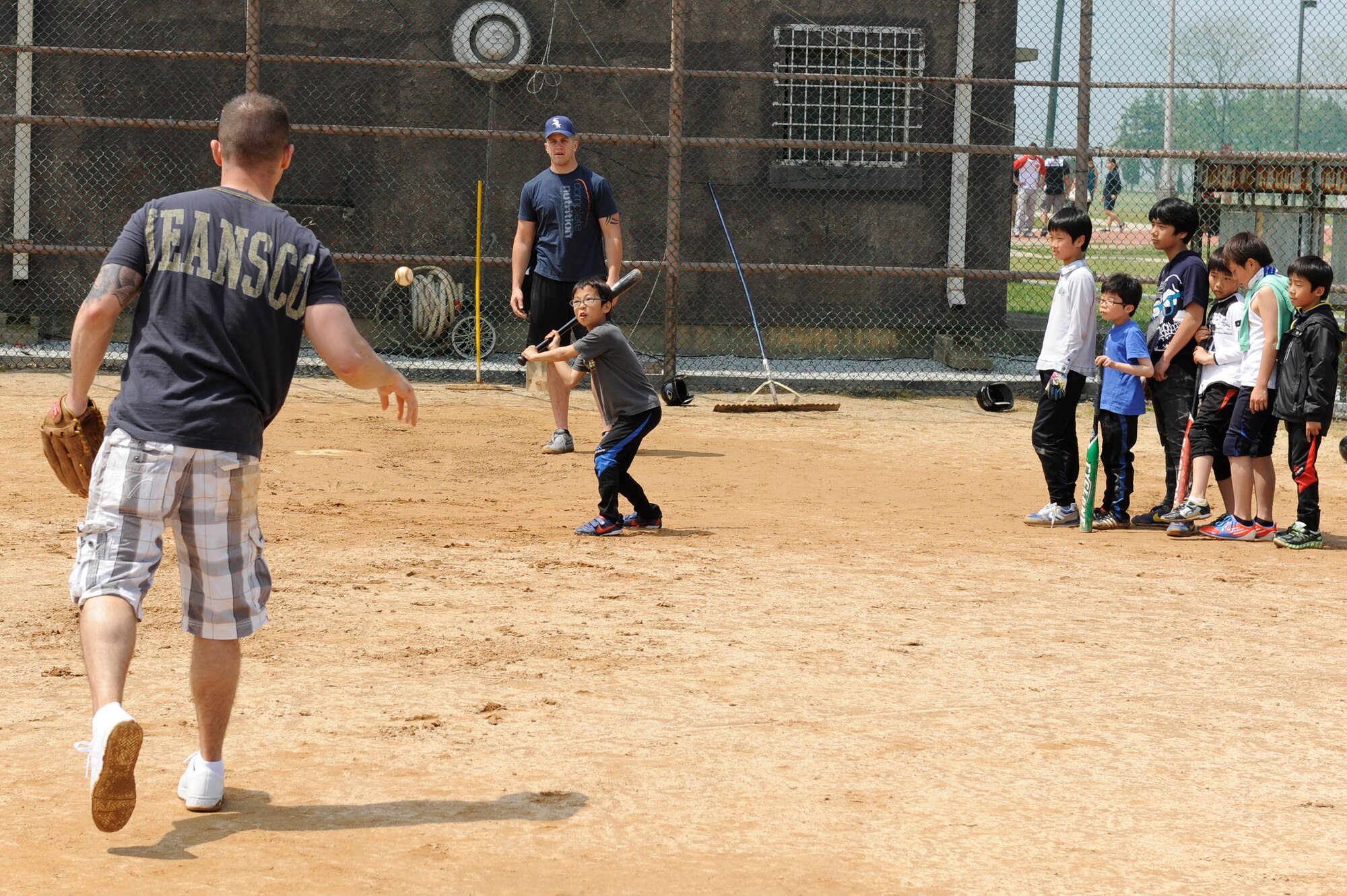 Children from Ilmagwon Orphanage take turns batting as Tech. Sgt. Matthew Such, 8th Comptroller Squadron, pitches the ball during a sports day event at Kunsan Air Base, Republic of Korea, May 11, 2013. This was the first of a number of sports days that the base plans on having for the youth this year. (U.S. Air Force photo by Senior Airman Marcus Morris/Released)