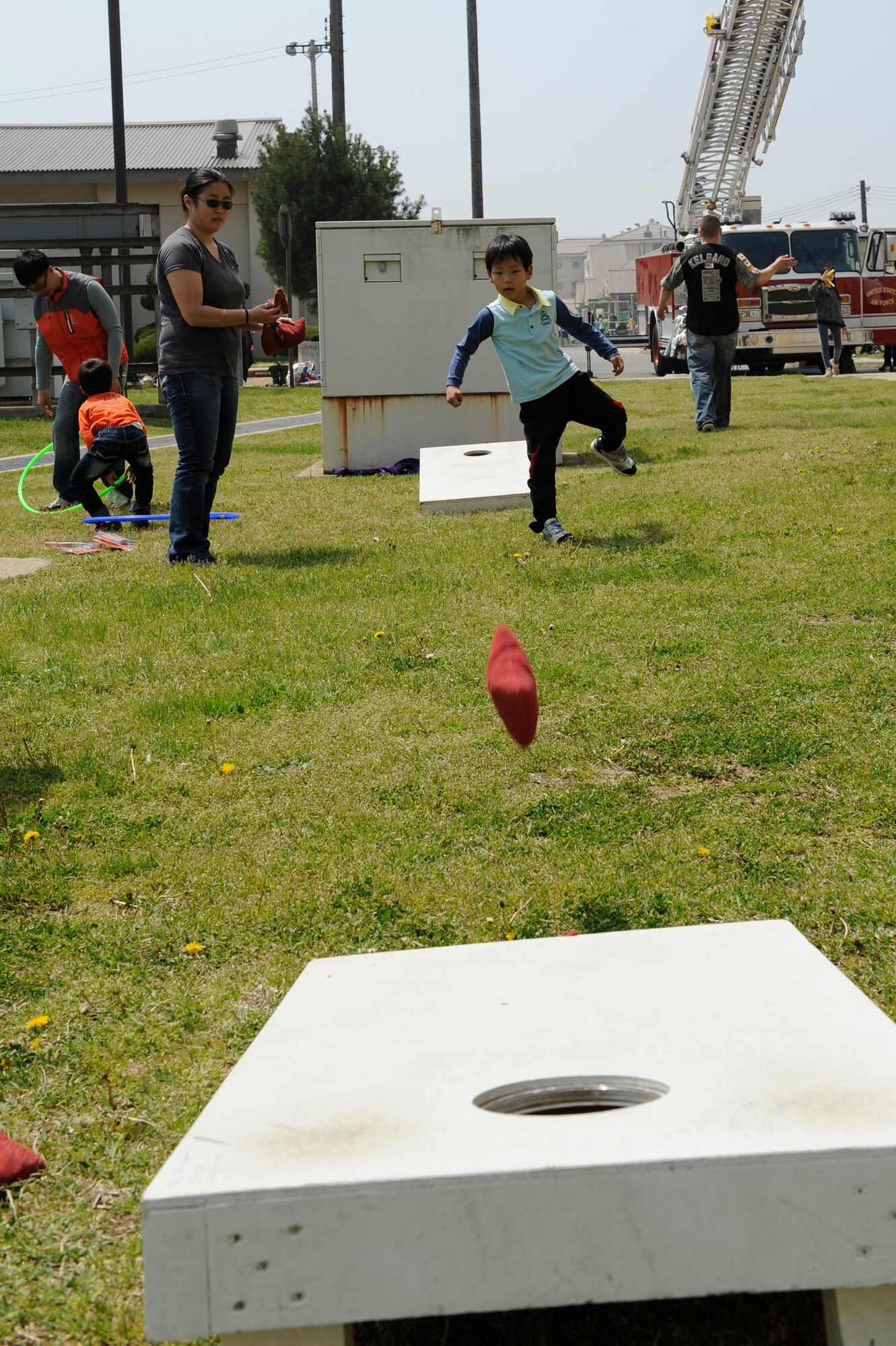 A child from Ilmagwon Orphanage tosses a bean bags as Staff Sgt. Sara Yarian, 8th Maintenance Squadron, watches during sports day at Kunsan Air Base, Republic of Korea, May 11, 2013. This event was sponsored by the Air Force Sergeants Association to bring children from the Orphanage to play games and experience new things. (U.S. Air Force photo by Senior Airman Marcus Morris/Released)