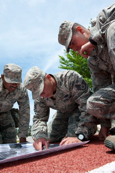 8th Security Forces Squadon members, Staff Sgt. Luis Velasquez (center) plots a point on a map while Airman 1st Class’ Raymond Washington (left) and Edmund Oropeza (right) watch at Kunsan Air Base, Republic of Korea, May 17, 2013. The Bravo flight members participated in a special defenders’ challenge that required them to determine where each event would occur based on coordinates they were given.  (U.S. Air Force photo by Staff Sgt. Jonathan Fowler/Released)