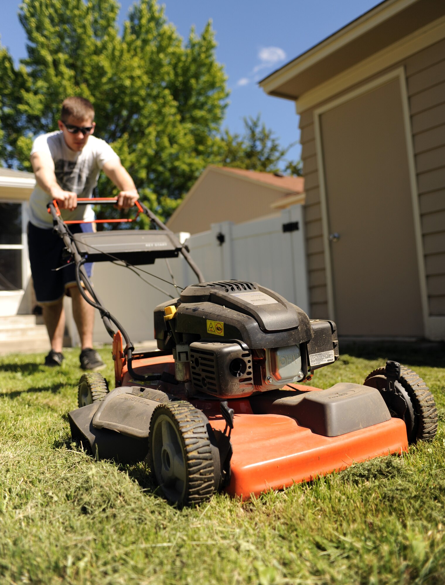 Senior Airman Taylor Curry mows his backyard at Fairchild Air Force Base, Wash., June 4, 2013. Balfour Beatty manages family housing on base and upholds standards for lawn appearance. (U.S. Air Force photo by Airman 1st Class Sam Fogleman/Released)