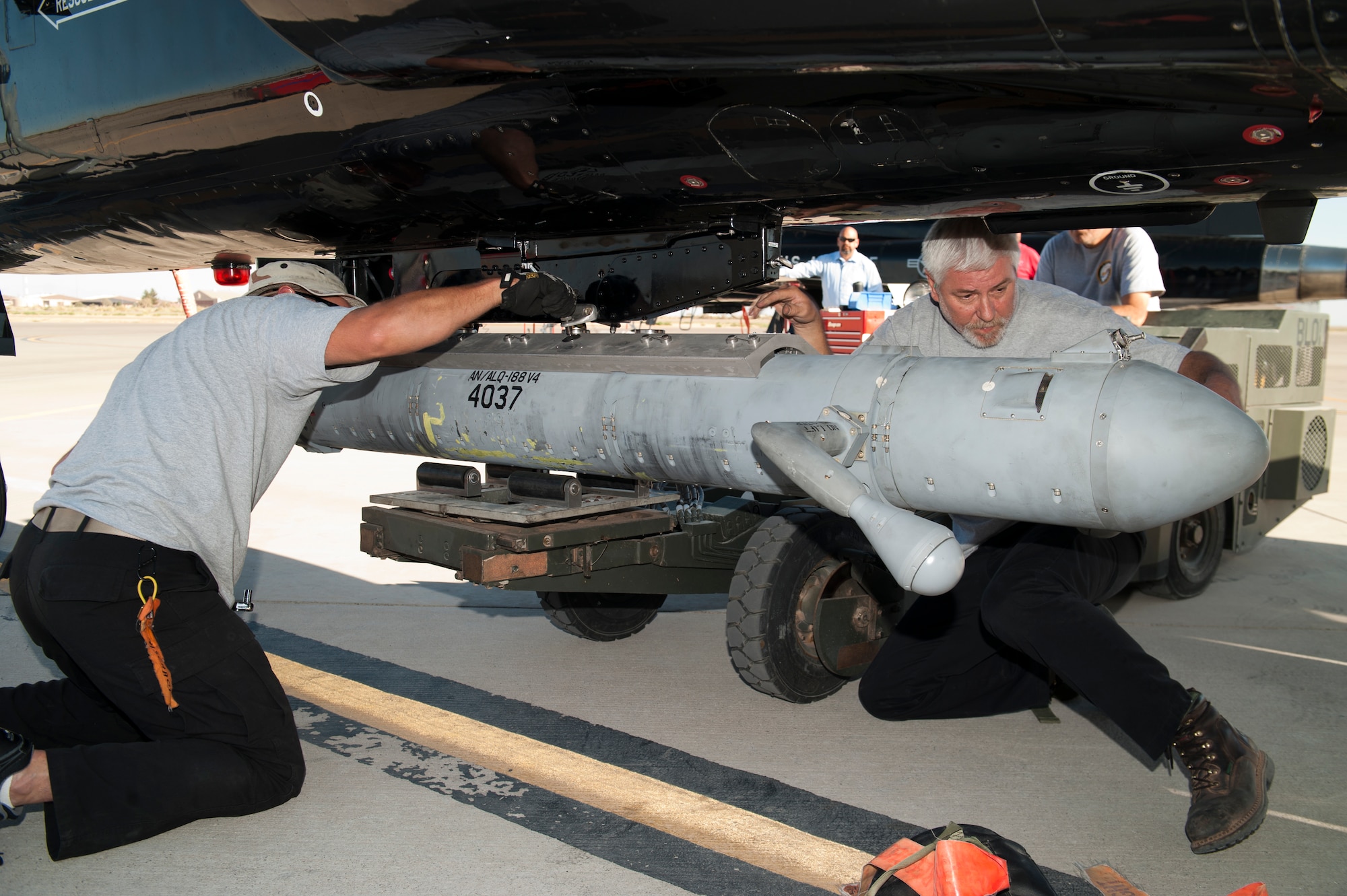 Ronald Legand, and Jeremy Hale, both M1 Support Services maintainers, attach a radar jammer pod onto a T-38 Talon at Holloman Air Force Base, N.M., Jun 4. For the first time, the T-38 has been modified to fit the ALQ-188 pod for use as a radar jammer. This newest addition to the T-38 will assist in its training mission by making it a more effective adversary for the F-22 Raptor during simulated combat exercises. (U.S. Air Force photo by Airman 1st Class Daniel E. Liddicoet/Released)